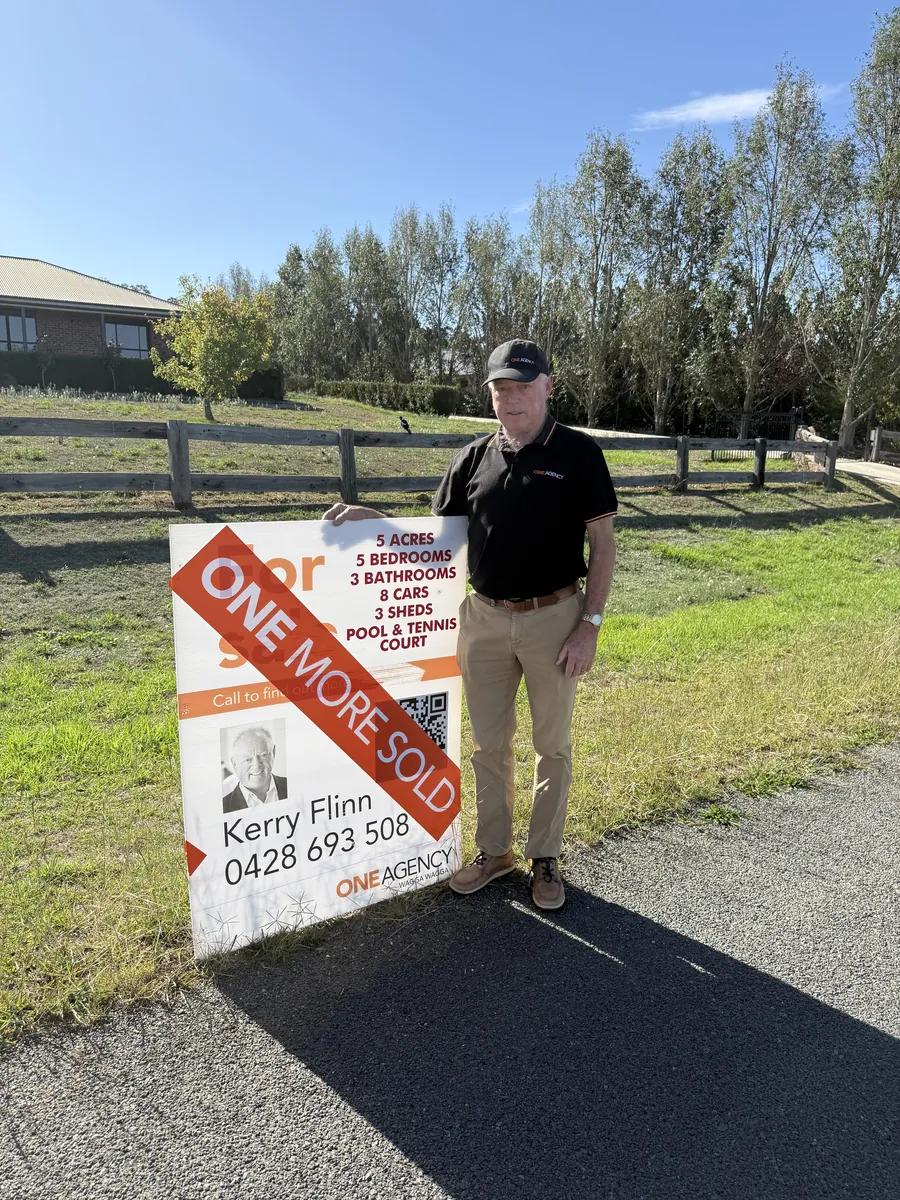 Kerry Flinn beside a sold sign at a Wagga Wagga property